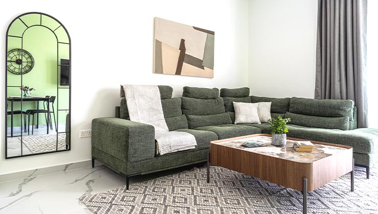 abraj 202 apartment modern living room couch and table and mirror reflecting chairs and table.